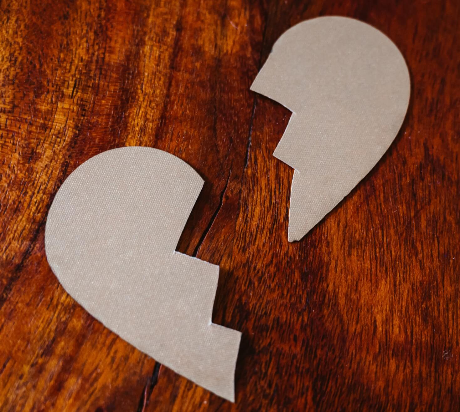 two pieces of a broken paper heart on a wooden table