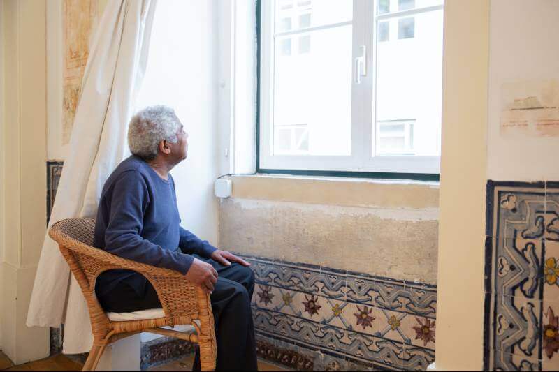elderly man staring out a window