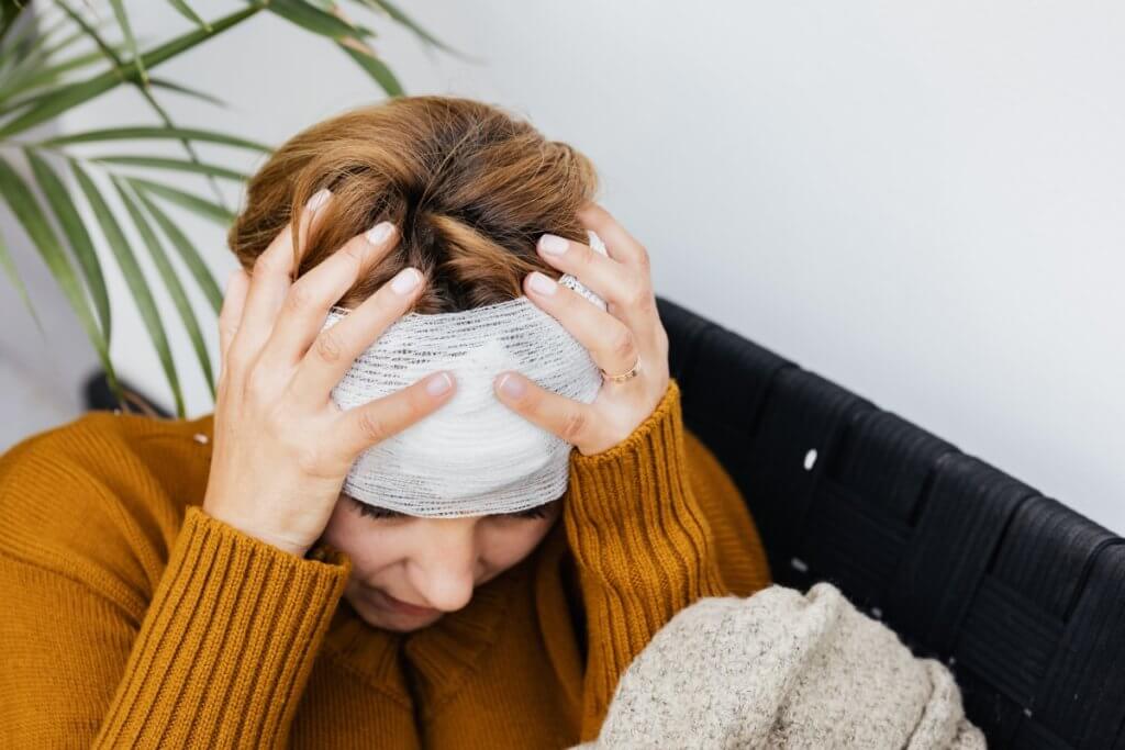 an image of a woman with a bandage on her head and her hands holding it for personal injury